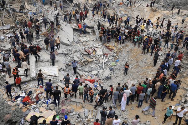 Civilians and rescuers search for survivors under the rubble of a decimated building in Khan Yunis, located in the southern Gaza Strip, following an Israeli airstrike, which occurred in the midst of the ongoing conflict between Israel and the Palestinian militant group, Hamas. - Sputnik International