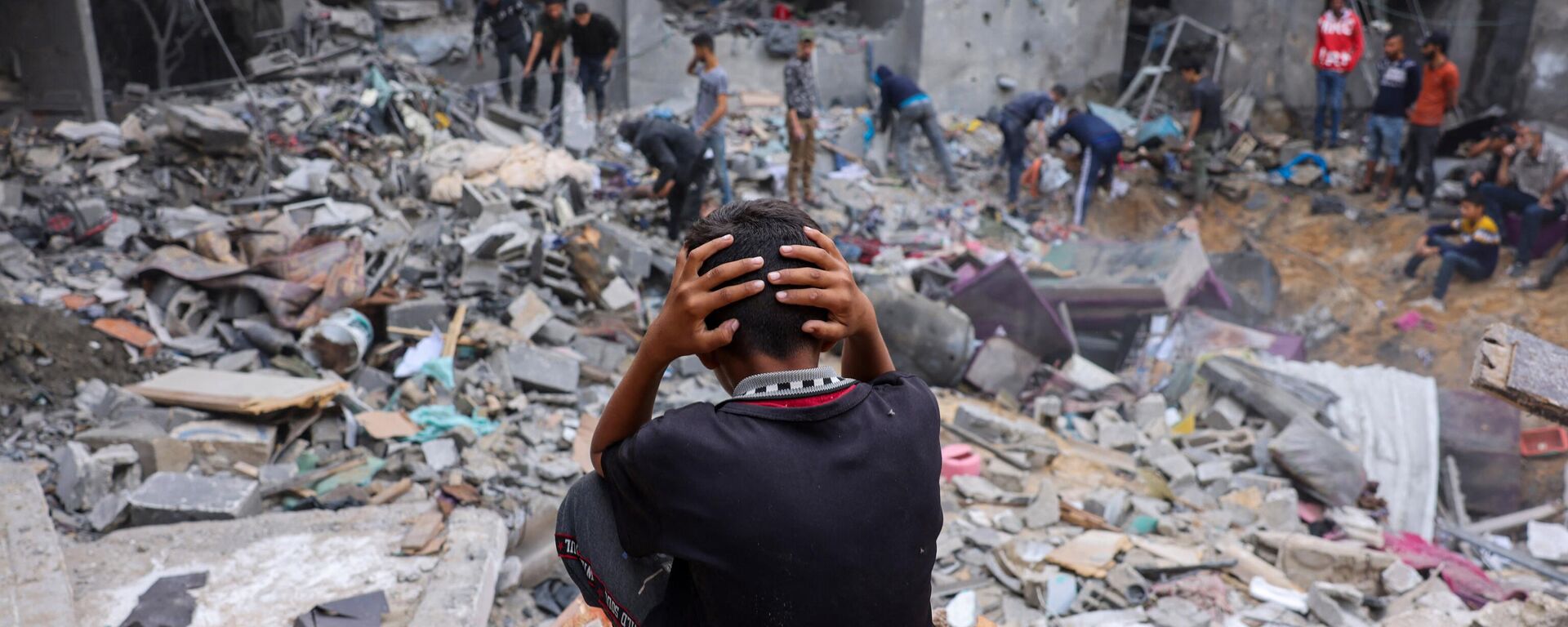 A child reacts as people salvage belongings amid the rubble of a damaged building following strikes on Rafah in the southern Gaza Strip. - Sputnik International, 1920, 15.11.2023