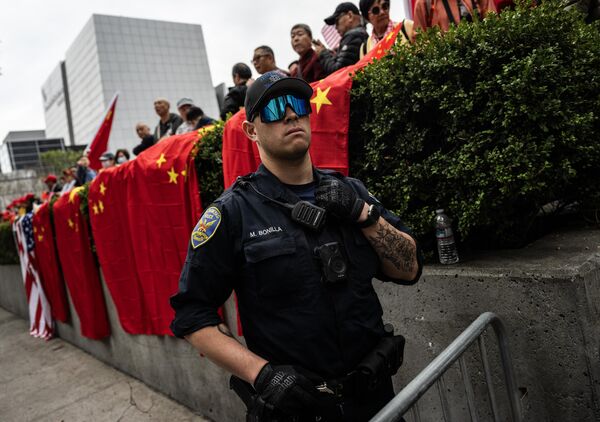 A police office looks on happily as supporters await the arrival of China&#x27;s President Xi Jinping next to the Asia-Pacific Economic Cooperation summit headquarters in San Francisco. - Sputnik International