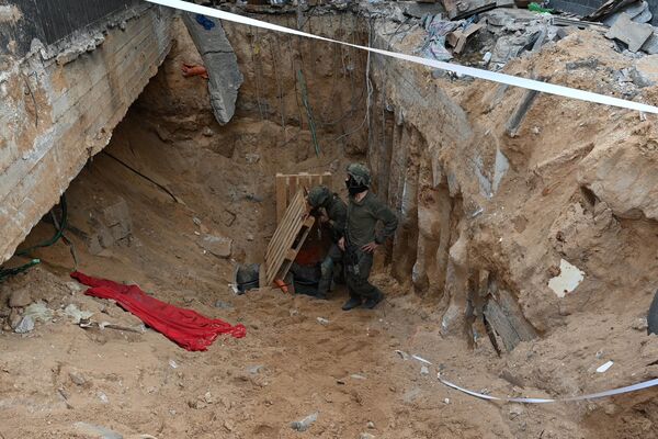 Soldiers stand next to what the Israeli Army says is the entrance to a tunnel dug by Hamas militants inside the Al-Shifa hospital. - Sputnik International