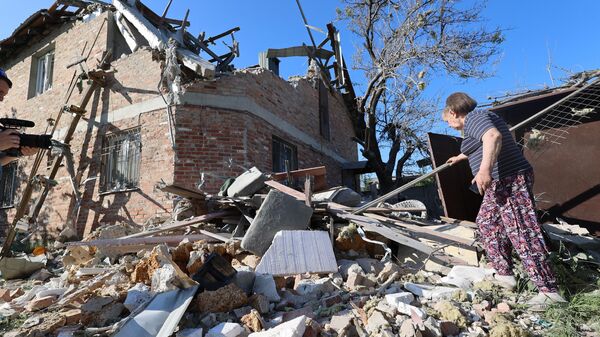 A local resident walks among debris next to a residential house damaged by Ukrainian shelling in the course of Russia's military operation in Ukraine, in Kuibyshev district of Donetsk, Donetsk People's Republic, Russia - Sputnik International