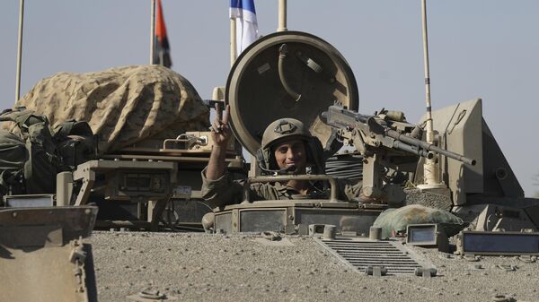 An Israeli soldier flashes a V-sign from a convoy of Israeli army vehicles after leaving Gaza, southern Israel, on Friday, Nov. 24, 2023. - Sputnik International