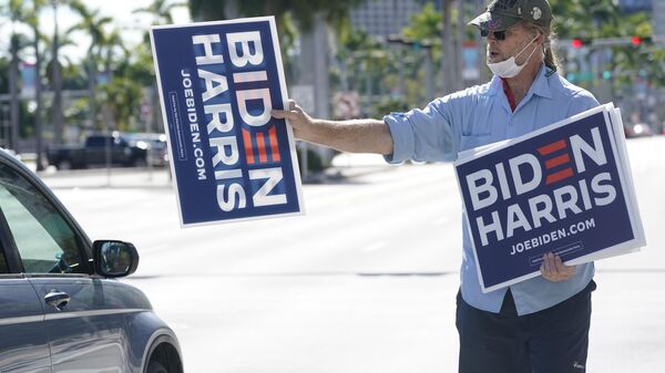 Bob Remmen gives out Biden Harris signs next to a site where people gathered to watch the inauguration of President Joe Biden on a mobile screen, Wednesday, Jan. 20, 2021, outside the famed Freedom Tower in downtown Miami. - Sputnik International