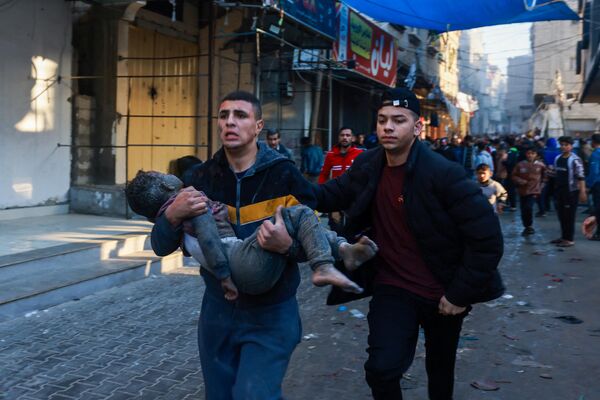 A Palestinian man carries an injured boy following the resumption of the Israeli bombardment in Rafah, southern Gaza Strip, on December 1, 2023, as fighting broke out shortly after the expiration of a seven-day truce between Israel and Hamas. - Sputnik International