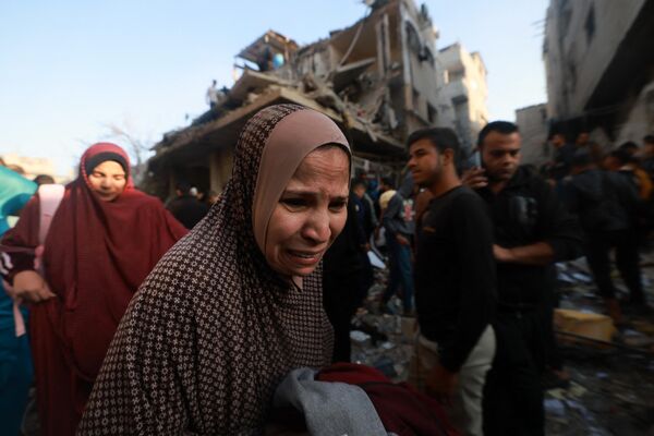 A Palestinian woman reacts as people check the rubble of a building destroyed in an Israeli air strikes on the Rafah refugee camp in the southern Gaza Strip on December 1, 2023. - Sputnik International