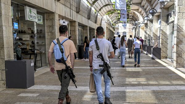 Israeli men, armed with US-made M16 automatic assault rifles, walk in a shopping centre in Jerusalem on October 25, 2023, amid the ongoing battles in the Gaza Strip between Israel and the Palestinian group Hamas. - Sputnik International