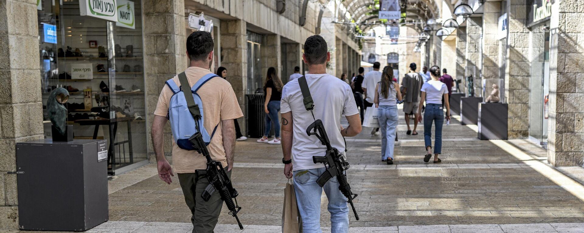 Israeli men, armed with US-made M16 automatic assault rifles, walk in a shopping centre in Jerusalem on October 25, 2023, amid the ongoing battles in the Gaza Strip between Israel and the Palestinian group Hamas. - Sputnik International, 1920, 13.12.2023