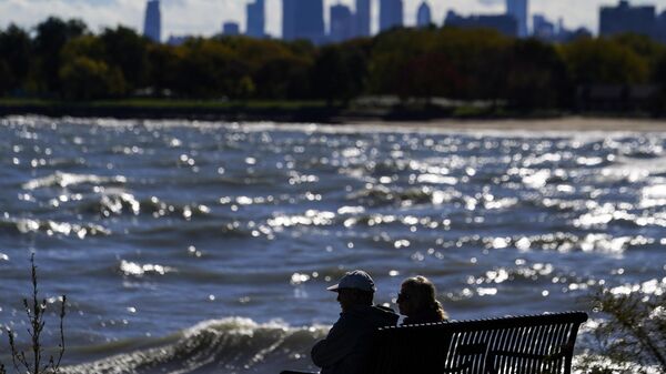 A couple sits on the bench on the shore of Lake Michigan as the downtown skyline is seen in the background, Sunday, Oct. 22, 2023, in Chicago. - Sputnik International