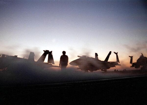 The sun sets over the flight deck of the USS Enterprise as crewmen prepare to launch the fourth wave of air strikes against Iraq on December 19, 1998 during Operation Desert Fox. - Sputnik International