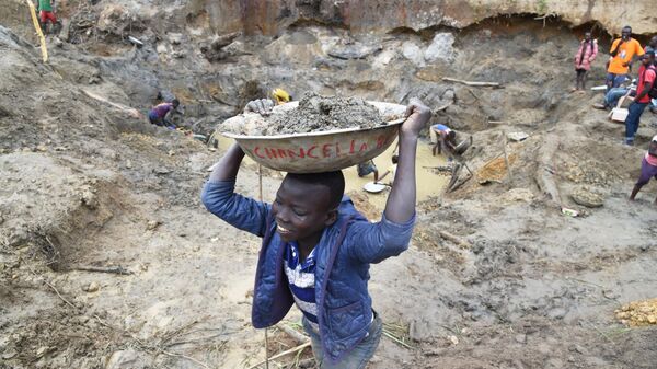 A child gold miner holds a bowl of earth on his head on May 5, 2014 while looking for gold in a traditional mine in the village of Gam, where gold mining in the main business activity of the region - Sputnik International