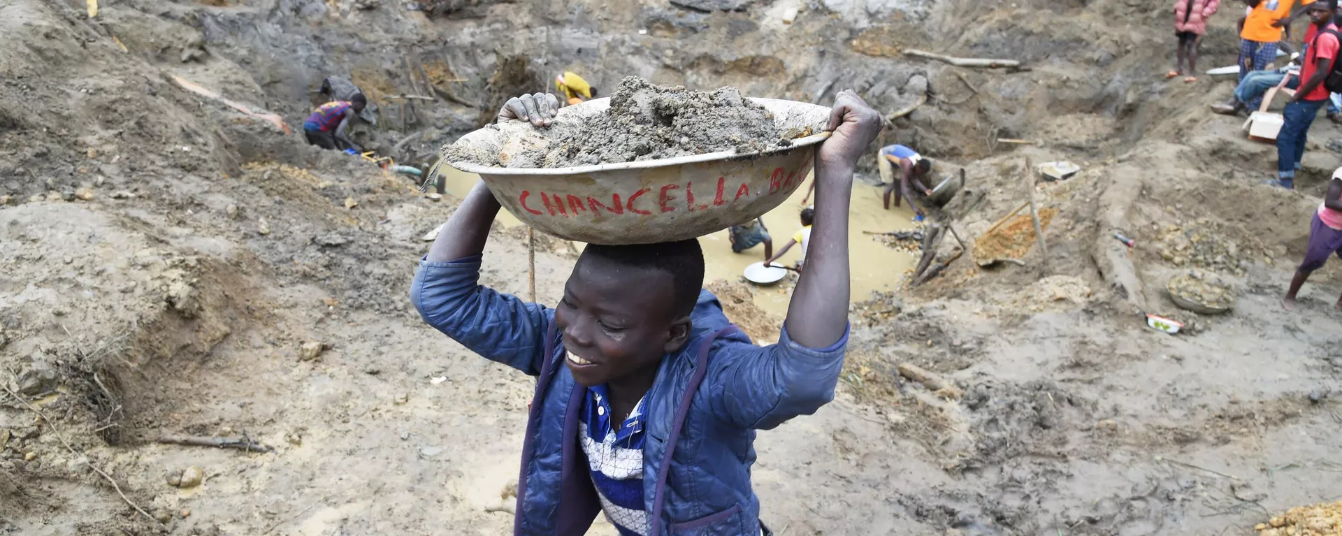 A child gold miner holds a bowl of earth on his head on May 5, 2014 while looking for gold in a traditional mine in the village of Gam, where gold mining in the main business activity of the region - Sputnik International, 1920, 17.12.2023