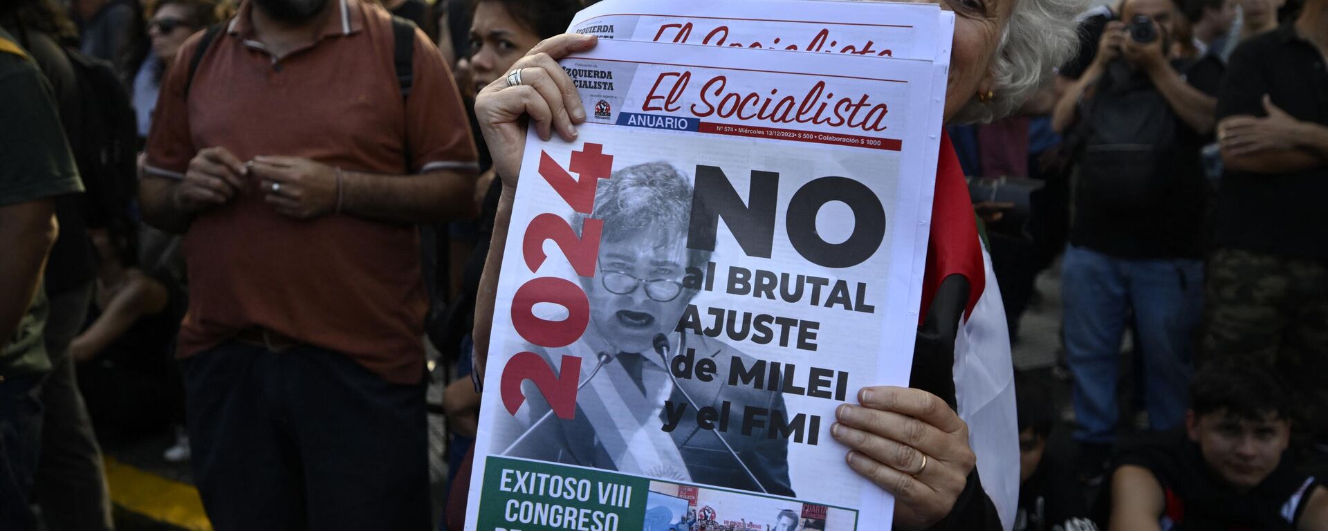 A woman holds a newspaper with a message against the economic adjustment during the first demonstration against the new government of Javier Milei at Plaza de Mayo Square in Buenos Aires on December 20, 2023 - Sputnik International, 1920, 20.12.2023