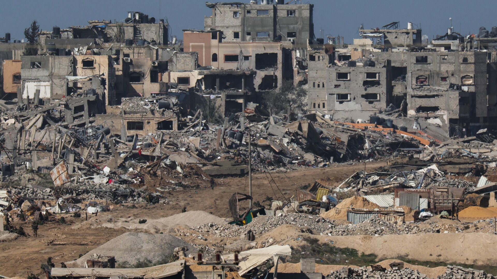 A picture taken from southern Israel bordering the Gaza Strip on December 22, 2023, shows an Israeli army tank rolling past debris of buildings in the Gaza Strip. - Sputnik International, 1920, 30.12.2023