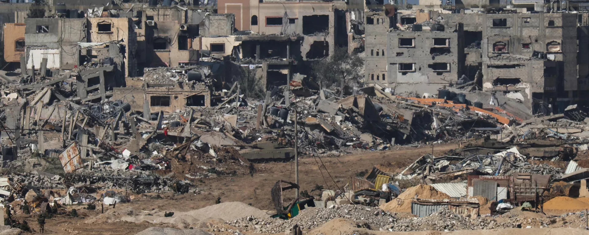 Zdjęcie zrobione z południowego Izraela graniczącego ze Strefą Gazy 22 grudnia 2023 r. pokazuje czołg armii izraelskiej przetaczający się obok gruzów budynków w Strefie Gazy. - Sputnik International, 1920, 30.12.2023