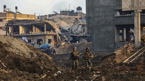  This picture taken on December 19, 2023, shows Israeli soldiers walking past damaged buildings during a military operation in the north of the Gaza Strip. - Sputnik International
