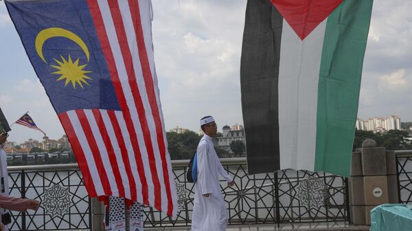 A Muslim walks to Friday prayer as Malaysia and Palestine flags on display in Putrajaya, Malaysia, Friday, Dec. 22, 2017. Malaysia Prime Minister Najib Razak leads huge rally to protest US move to recognize Jerusalem as Israel's capital. (AP Photo/Vincent Thian) - Sputnik International