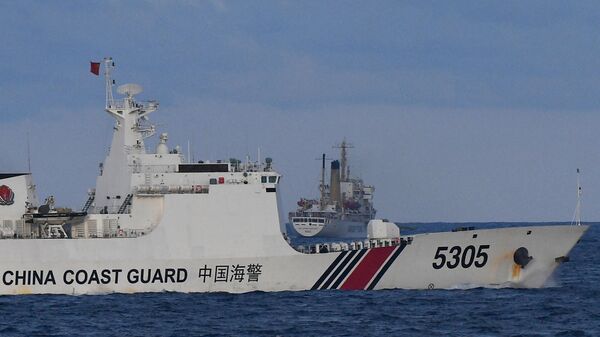 A Chinese Coast Guard ship sails near a Philippine vessel (C) that was part of a convoy of civilian boats in the disputed South China Sea on December 10, 2023.  - Sputnik International