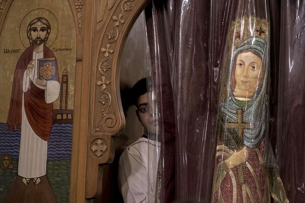 A Coptic Christian peers out of a window during an Orthodox Christmas Eve Mass at the Church of Ava Bishoy and St. Karas the Anchorite in Cairo, Egypt.   - Sputnik International