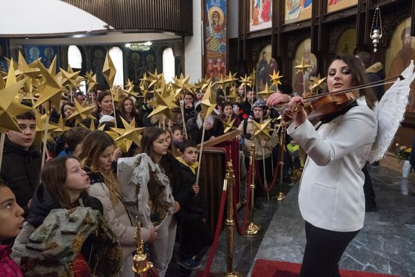 Children holding sticks decorated with stars sing religious songs during a religious service to celebrate Orthodox Christmas in St. Clement Cathedral in Skopje, North Macedonia. - Sputnik International