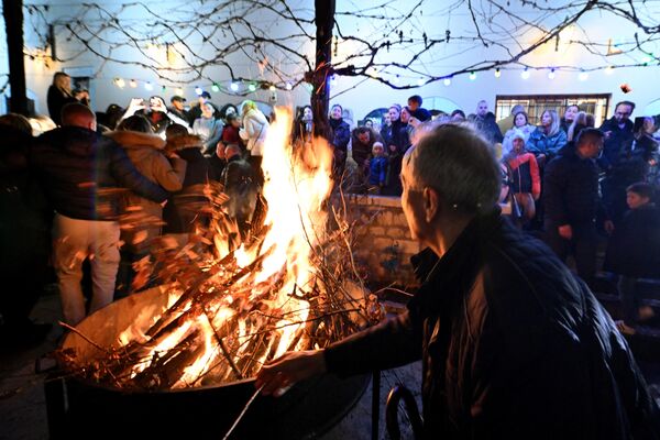 A man throws a branch into the fire as Sarajevo Orthodox Christians attend the annual bonfire of dried oak branches to mark the Orthodox Christmas Eve, at the Church of the Holy Archangels Michael and Gabriel, in Sarajevo, Bosnia and Herzegovina. - Sputnik International