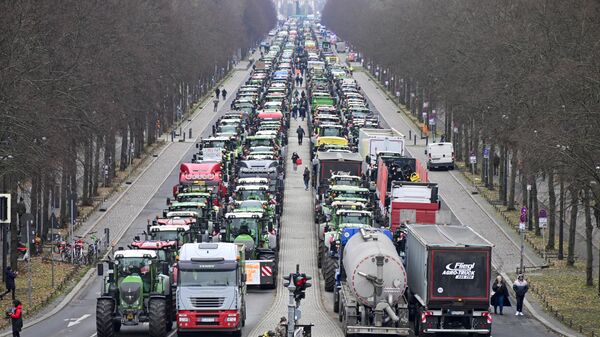 Tractors are lined up in the Strasse des 17 Juni boulevard, towards the Brandenburg Gate in Berlin, on December 18, 2023, as German farmers demonstrate against the planned abolition of subsidies for agricultural diesel. - Sputnik International