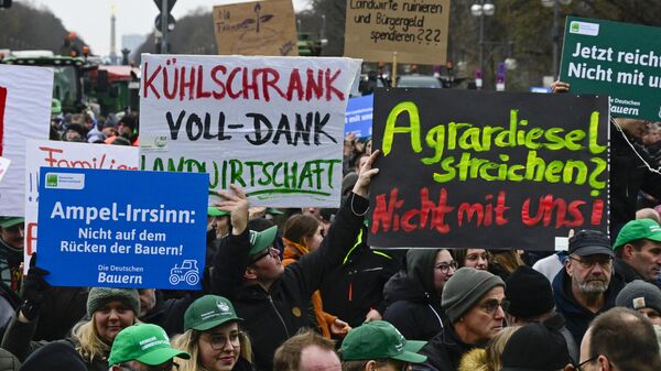 Demonstrators hold placards reading (L-R) Ampel madness, not on the back of the farmers, Refrigerator full - Thanks Agriculture and Cancelling agricultural diesel? Not with us! in the Strasse des 17 Juni boulevard, towards the Brandenburg Gate in Berlin, on December 18, 2023, during a demonstration of German farmers against the planned abolition of subsidies for agricultural diesel - Sputnik International