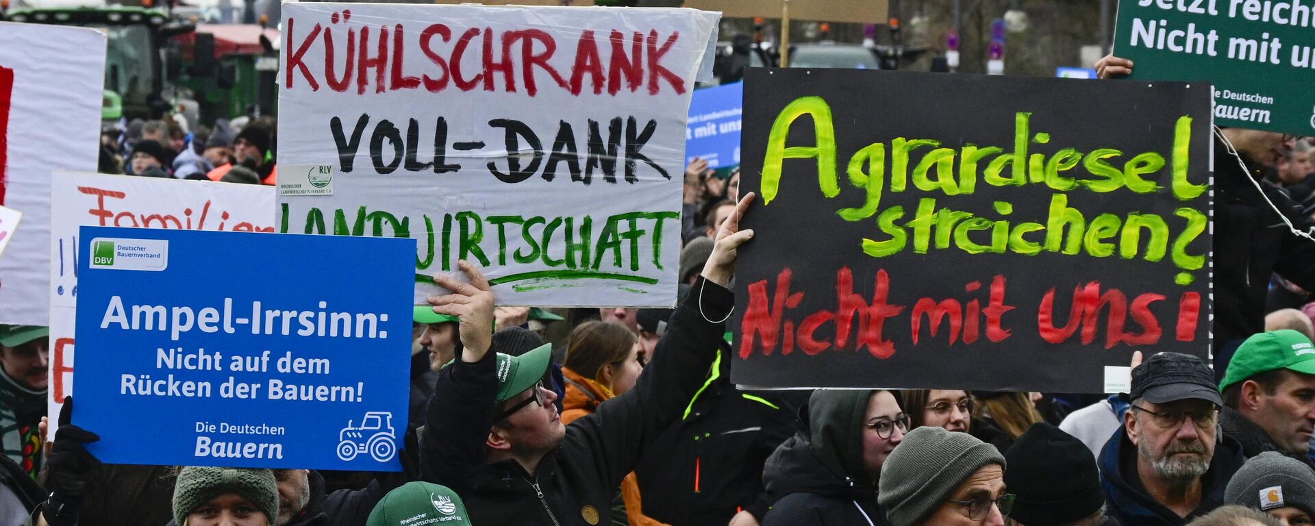 Demonstrators hold placards reading (L-R) Ampel madness, not on the back of the farmers, Refrigerator full - Thanks Agriculture and Cancelling agricultural diesel? Not with us! in the Strasse des 17 Juni boulevard, towards the Brandenburg Gate in Berlin, on December 18, 2023, during a demonstration of German farmers against the planned abolition of subsidies for agricultural diesel - Sputnik International, 1920, 10.01.2024
