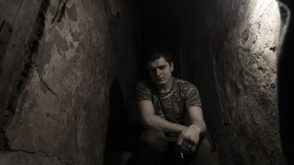 A Ukrainian serviceman smokes in a shelter at a position at the line of separation. - Sputnik International