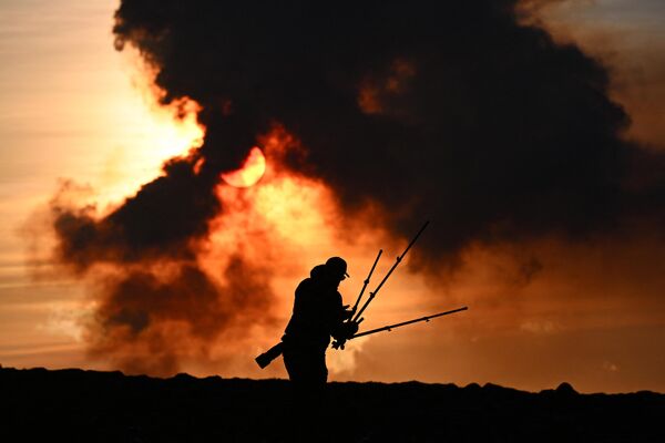 A man adjusts his photographic equipment near Keflavik, Iceland, as the plumes of smoke rise during the volcanic eruption. - Sputnik International