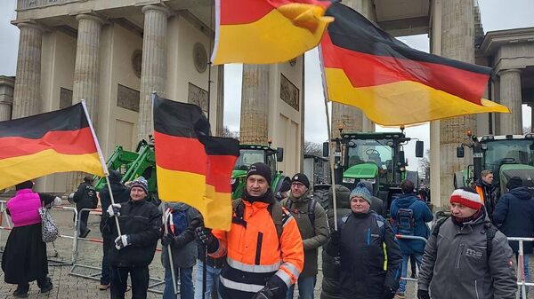 German farmers gather in front of the Brandenburg Gate in Berlin to protest government plans to cut agricultural subsidies and impose 'green farming' restrictions. - Sputnik International