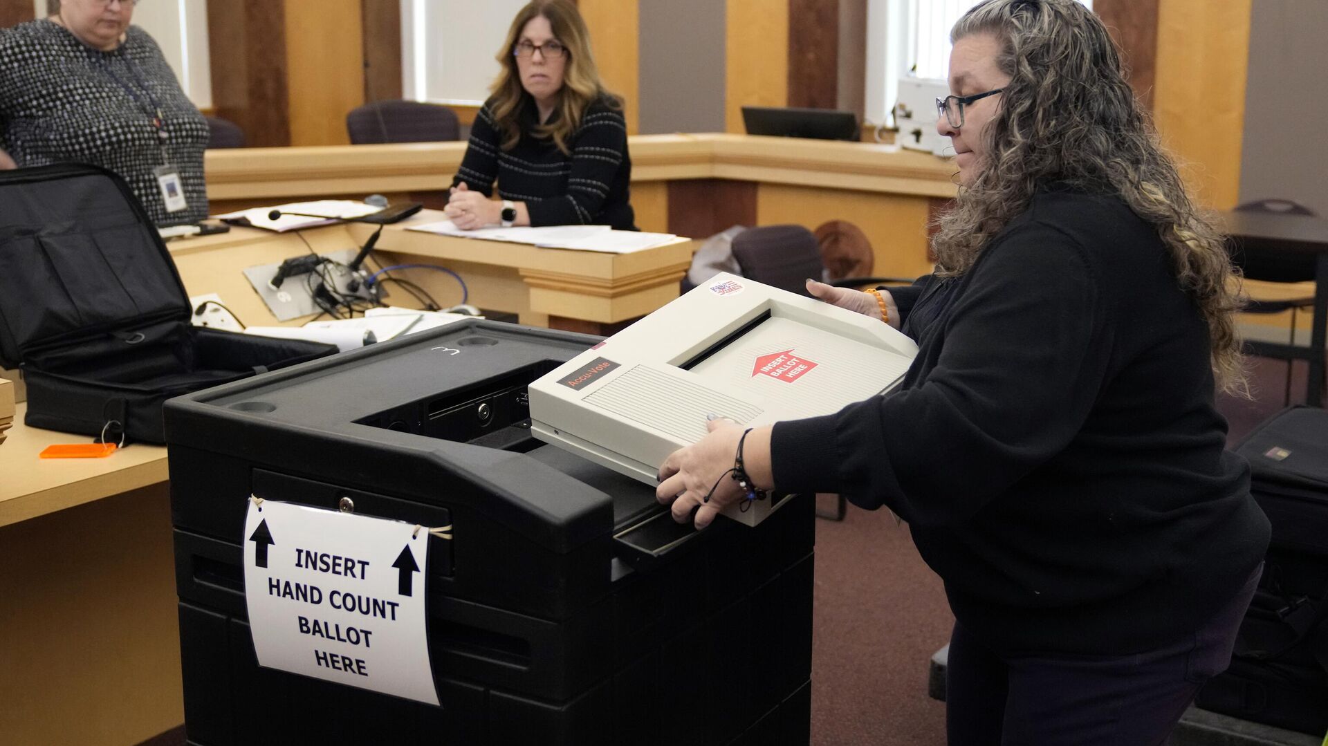 Lisa Hultgren, the Derry, N.H. town moderator, loads a vote counting machine into a cart, which stores the paper ballots, while testing vote counting machines before the New Hampshire primary at the Derry Municipal Center, Tuesday, Jan. 16, 2024. At left is Tina Guilford, Derry town clerk and at center is Lynne Gagnon, Derry deputy town clerk - Sputnik International, 1920, 21.01.2024