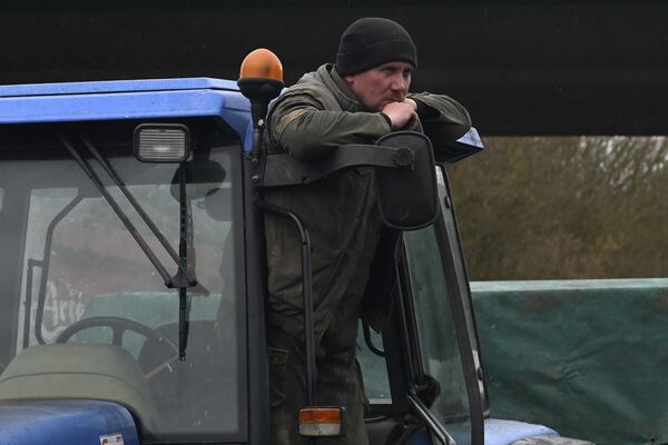 A French farmer stands on his tractor as farmers block a highway near Beauvais, northern France. Farmers have for months been protesting for better pay and against what they consider to be excessive regulation, mounting costs, and other problems. - Sputnik International