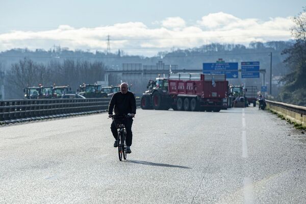 A man rides his bicycle as farmers block the Hubert Touya viaduct on a highway in Bayonne. - Sputnik International
