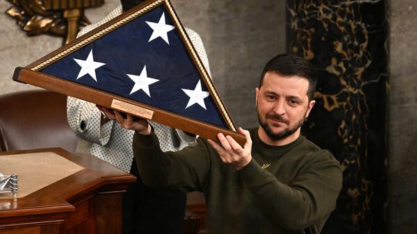 Ukraine's President Volodymyr Zelensky holds a US national flag he received from US House Speaker Nancy Pelosi (D-CA) (L) during his address to the US Congress at the US Capitol in Washington, DC on December 21, 2022.  - Sputnik International