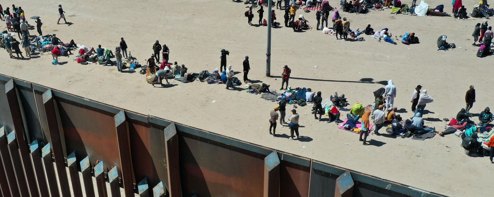 An aerial image shows migrants waiting along the border wall to surrender to Border Patrol agents for immigration and asylum claim processing after crossing the Rio Grande river into the US on the US-Mexico border in El Paso, Texas on May 11, 2023 - Sputnik International, 1920, 14.02.2024