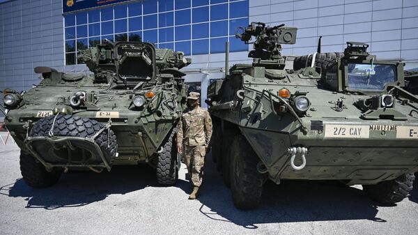 A US soldier stands between a Joint light Tactical vehicle (L) and a Stryker Infantry carrier vehicle during the 15th Defence Equipment and Services Exhibition HEMUS-Defence, Anti-terrorism and Security in Plovdiv, Bulgaria, on June 1, 2022.  - Sputnik International