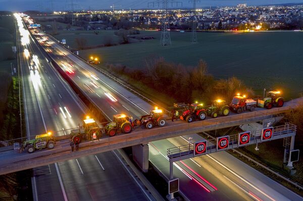 Farmers engage in a collective demonstration by parking their tractors on a small bridge over a highway in Frankfurt, Germany. - Sputnik International