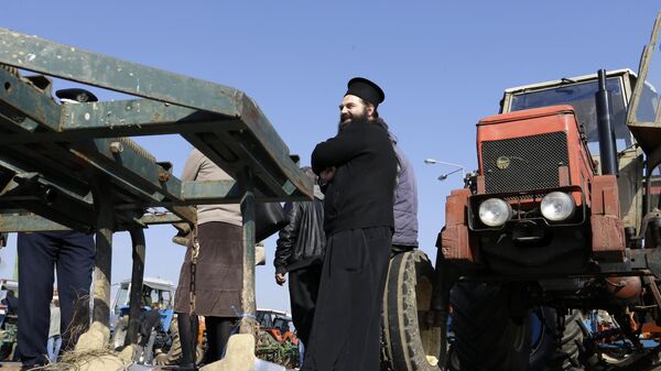 A Greek Orthodox priest stands with protesting farmers as they block a road that links the international airport with the southern and eastern suburbs of the Greek capital, in Koropi, near Athens, Friday, Jan. 29, 2016. - Sputnik International