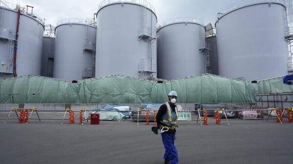A worker helps direct a truck driver as he stands near tanks used to store treated radioactive water after it was used to cool down melted fuel at the Fukushima Daiichi nuclear power plant, run by Tokyo Electric Power Company Holdings (TEPCO) - Sputnik International
