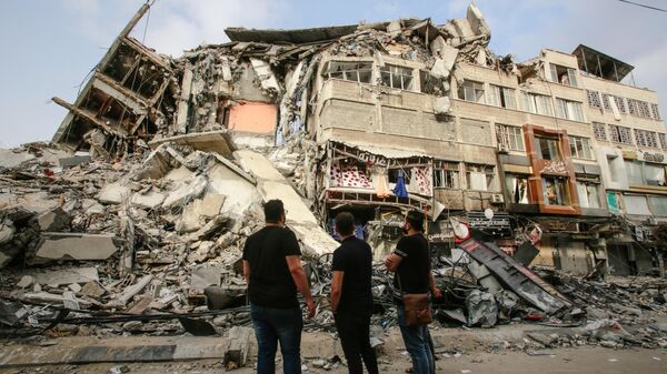 Palestinians look at ruins of a residential building - Sputnik International