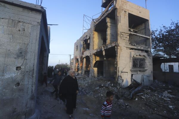 Locals walk by a residential building destroyed as a result of the Israeli attack.  - Sputnik International