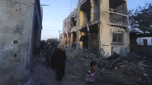 Palestinians walk by a residential building destroyed in an Israeli strike in Rafah, Gaza Strip, Sunday, Feb. 11, 2024 - Sputnik International