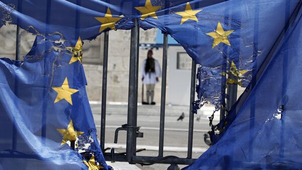 A Greek presidential guard stands framed bythe remains of a European Union flag half-burnt by protesters in Athens, on Wednesday, May 1, 2013 - Sputnik International