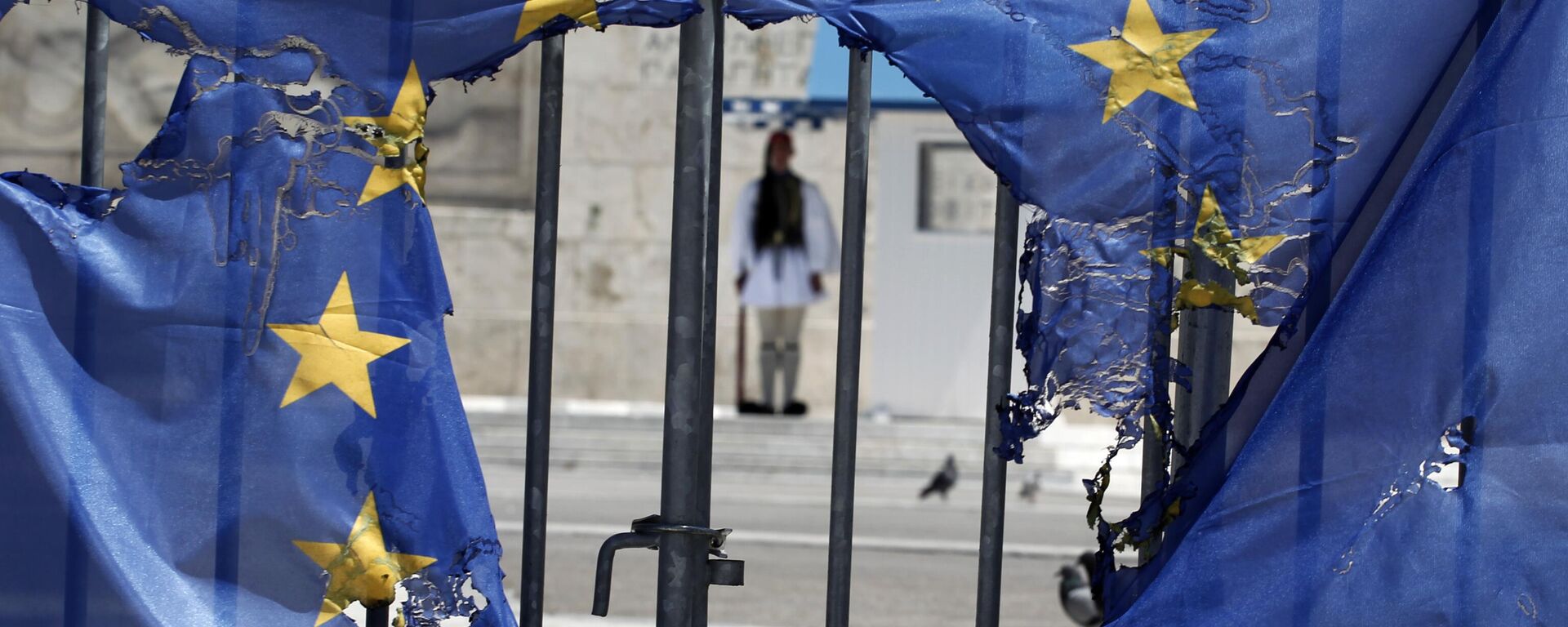A Greek presidential guard stands framed bythe remains of a European Union flag half-burnt by protesters in Athens, on Wednesday, May 1, 2013 - Sputnik International, 1920, 08.03.2024