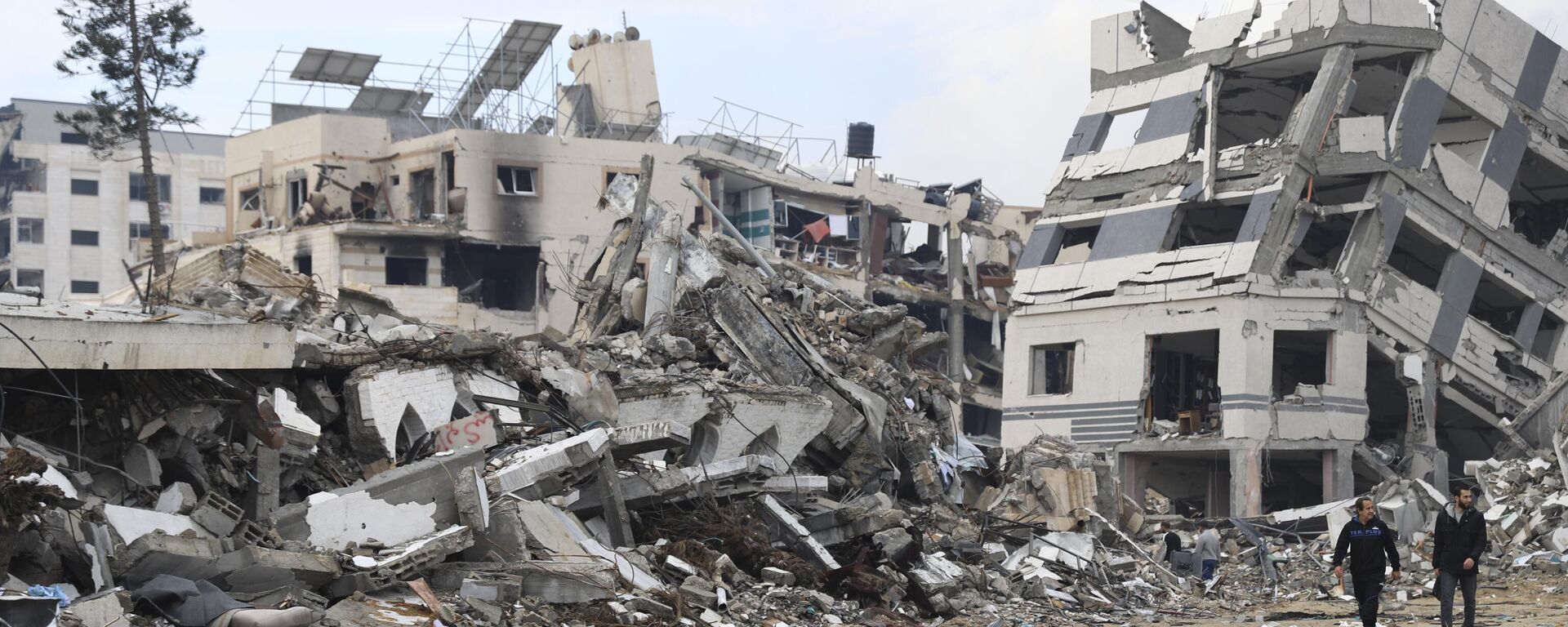 Palestinians walk past the building destroyed in the Israeli Bombardment of the Gaza Strip in Gaza City on Wednesday, Jan. 3, 2024 - Sputnik International, 1920, 28.03.2024