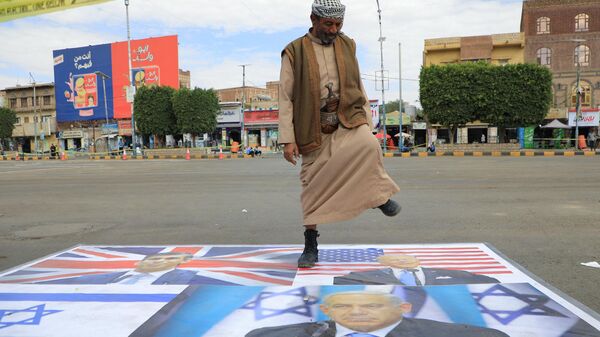 A supporter of Yemen's Huthi movement steps on images of Israeli and western flags and leaders as he takes part in a pro-Palestinian rally in Sanaa on February 8, 2024, amid the ongoing conflict in the Gaza Strip between Israel and the Palestinian militant group Hamas. - Sputnik International