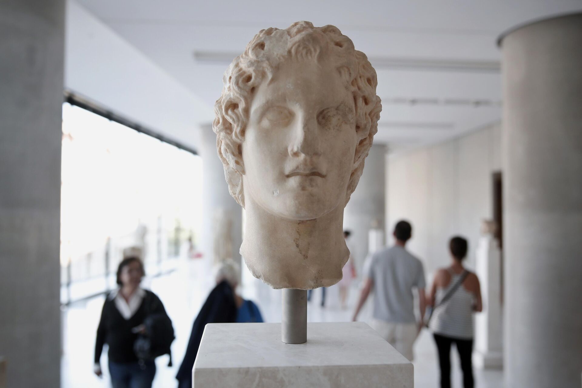 Visitors walk behind an ancient marble head of ancient Greek warrior-king Alexander the Great, displayed at the Acropolis museum in Athens, Oct. 12, 2014. Alexander the Great was one of the world's most successful military commanders, who enlarged his father's kingdom to include an empire stretching from modern Greece to India. During his youth, Alexander was tutored by the ancient Greek philosopher Aristotle until the age of 16.  - Sputnik International, 1920, 17.02.2024
