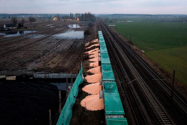 Piles of Ukrainian corn spilled on the ground next to train cars in Poland. - Sputnik International