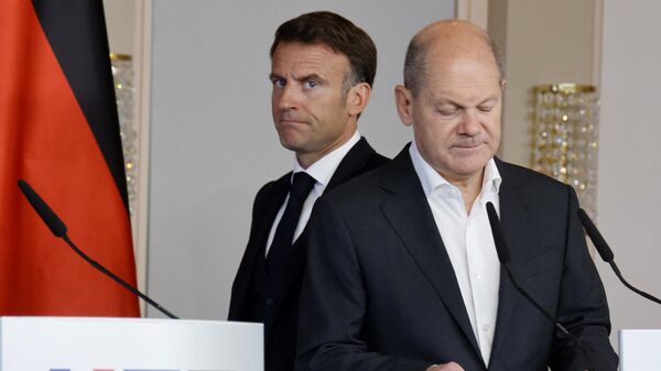 French President Emmanuel Macron (L) walks behind German Chancellor Olaf Scholz (R) as they arrive to address a joint press conference in Hamburg, northern Germany, on October 10, 2023, on the second day of two-day German-French government consultations.  - Sputnik International