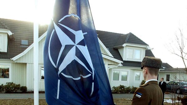An Estonian soldier holds NATO flag in front of the former Estonian President Lennart Meri's house in Tallinn 29 March 2004. - Sputnik International